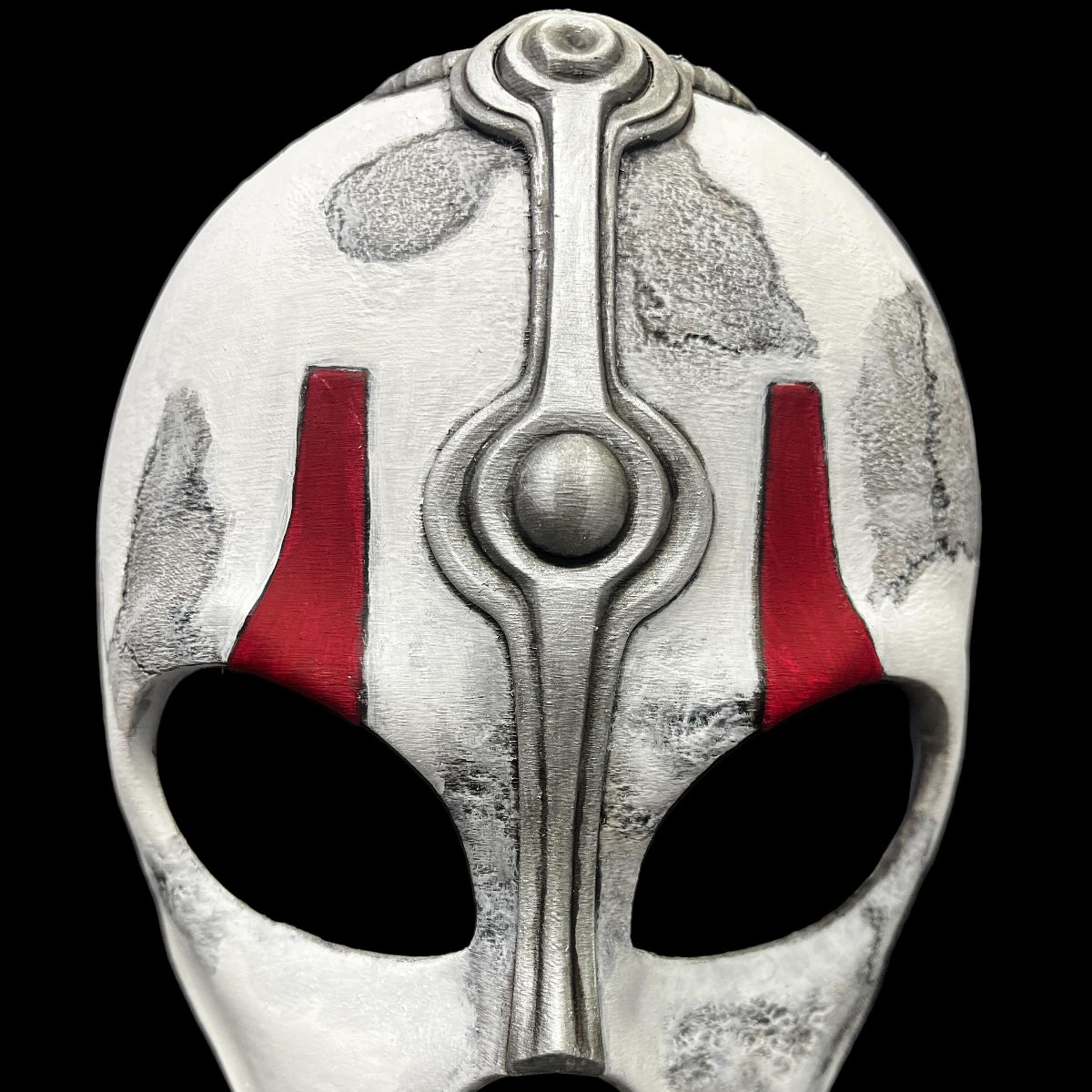 Decorative mask with silver and red design on a gray surface