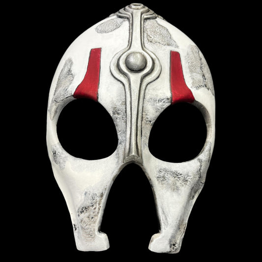 Decorative mask with white and red design on a gray surface