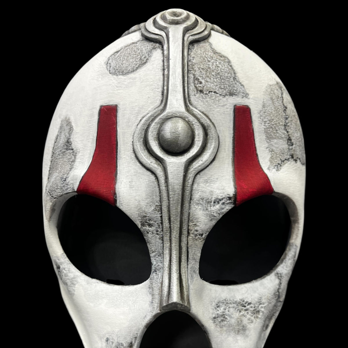 Decorative mask with red accents on a gray surface