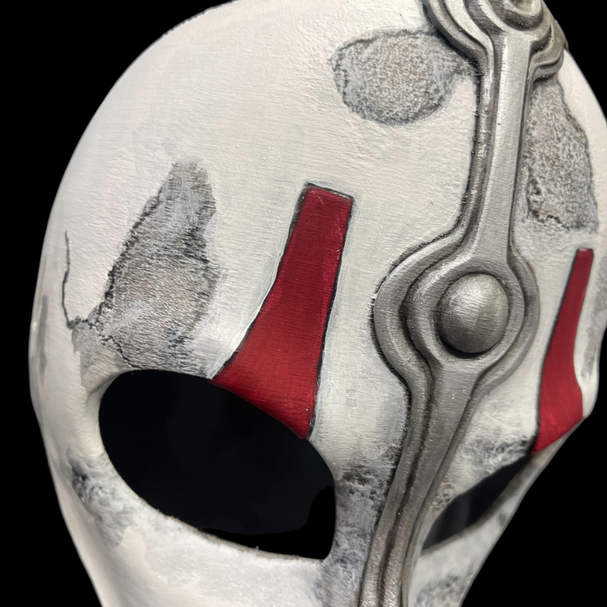 Close-up of a helmet with intricate design and red accents on a gray background